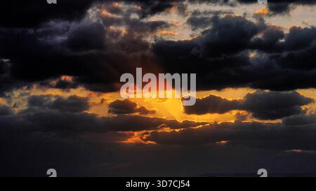 Dramatischer Sonnenuntergangshimmel Mit Sonnenstrahlen, Die Durch Dunkle Sturmwolken Brechen Stockfoto