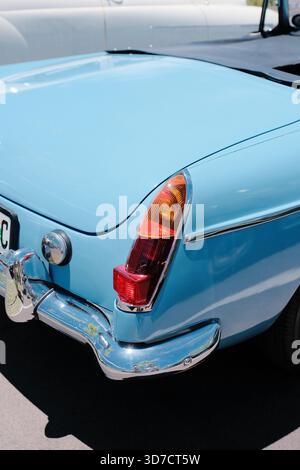 Nahaufnahme des Heckbereichs eines hellblauen Oldtimers mit Chromstoßfänger, klassischem Rücklicht, glatten Karosseriekonturen und Retro-Design. Stockfoto