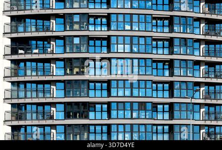 Fenstermuster erstrecken sich über die elegante Fassade eines Wolkenkratzers. Die Architektur aus blauem Glas und Metall spiegelt urbane Symmetrie wider und präsentiert einen modernen Büroturm Stockfoto