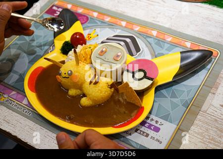 Der Tourist verwendet einen Löffel, um den Pokemon Cafe-Menüpunkt Pikachu and Squirtle's Best Friends Forever Curry Teller in Nihonbashi, Tokio, Japan zu essen Stockfoto