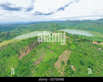 Blick aus der Vogelperspektive auf die ruhigen Twin Crater Lakes Katinda und Mirambi, eingebettet zwischen grünen Hügeln und bewirtschaftetem Land unter einem bewölkten Himmel, Twin Crater Lake Stockfoto