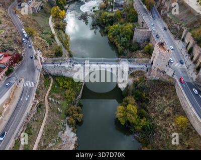 Aus der Vogelperspektive auf die alte Brücke Puente de San Martín, die sich über den Tejo erstreckt und die zerklüfteten Ufer mit einem Wandteppich aus Grün und Grün verbindet Stockfoto