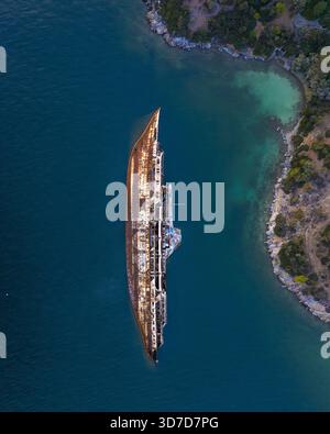 Aus der Vogelperspektive auf das verrostete MS Mediterranean Sky Wrack, das im kristallblauen Küstenwasser liegt, während die Sonne über der Küste von Athen, Griechenland, untergeht. Stockfoto