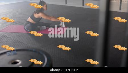 Eine dehnende Erwachsene Frau, die im Fitnessstudio auf rosa Matte nach Fuß streckt, schwarze Sportbekleidung trägt, Dollarzeichen Stockfoto