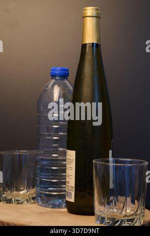 Eine Flasche Weißwein und eine Plastikflasche Wasser Stockfoto