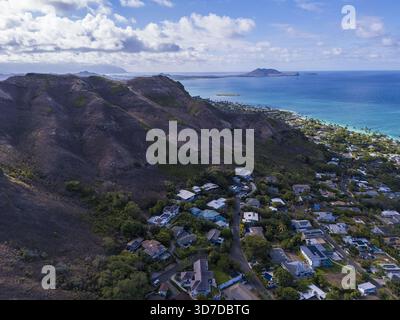 Die rauen Berghänge treffen aus der Vogelperspektive auf das türkisfarbene Wasser der Küste, im Kontrast zu den verstreuten Häusern darunter, Lanikai, Kailua, Hawaii Stockfoto