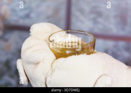 Hände in Handschuhen, die eine Tasse Tee halten Stockfoto