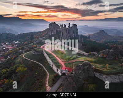 Aus der Vogelperspektive der alten Festungsmauern umschließen die zerklüfteten Belogradchik Felsen, die in den warmen Tönen der Morgendämmerung getaucht sind, Belogradchik, Vidin, Bulgarien. Stockfoto