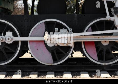 Detaillierte Ansicht alter Dampflokomotivräder und -Maschinen auf Eisenbahngleisen, mit industriellem Design und technischen Elementen in natürlichem Tageslicht Stockfoto