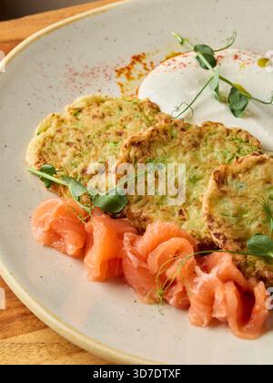 Köstliche Räucherlachs- und Zucchini-Pfannkuchen, Gourmet-Teller mit Meeresfrüchten und frischem Gemüse Stockfoto