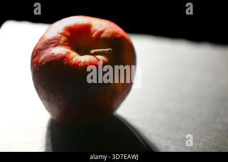 Extreme Nahaufnahme eines roten Apfels auf einer hellen Oberfläche mit starkem Kontrast und sauberer minimalistischer Zusammensetzung. Geeignet für gesunde Ernährung und Lebensmittel Kleie Stockfoto