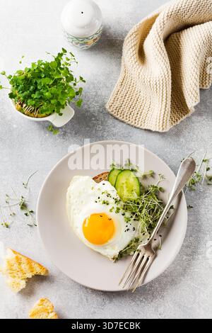 Traditionelles englisches Frühstück mit Spiegeleiern mit Rucola microgreen in grauer Keramikplatte auf grauem Beton altem Hintergrund. Draufsicht. Stockfoto