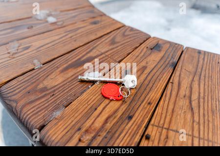 Verlorene Hausschlüssel liegen im Winter auf einer Bank Stockfoto