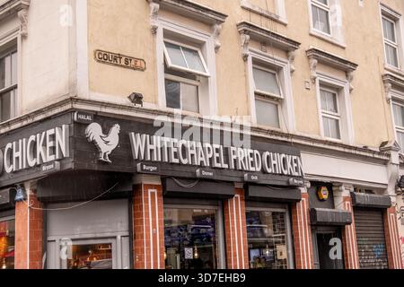 LONDON – 29. OKTOBER 2025: Whitechapel Fried Chicken, Court Street – Halal Take away und multikulturelles Straßenleben an einem regnerischen East London Day Stockfoto