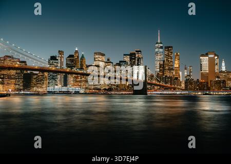 Blick über den East River zur Brooklyn Bridge mit der Skyline von New York bei Nacht Stockfoto