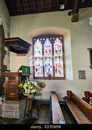 Vor der Holy Trinity Church, Ashford-in-the-Water, Peak District, Derbyshire. Das Haworth-Fenster stammt aus dem Jahr 1880. Es zeigt die sechs Werke von Mercy From Stockfoto