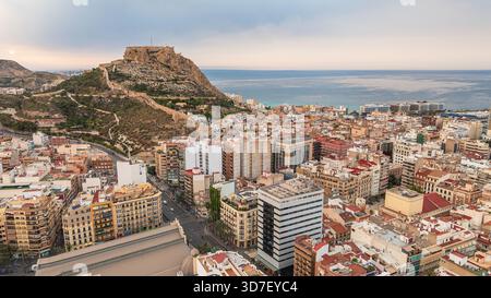 Alicante aus der Vogelperspektive nach Sonnenuntergang. Küstengebiete mit modernen Gebäuden, Hafen, Meer und Berge in der Ferne. Alicante ist eine Stadt in der valencianischen Gemeinde Stockfoto