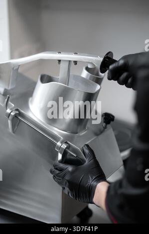 Nicht wiedererkennbarer Koch schneidet Gemüse mit industriellem Slicer in der Küche Stockfoto