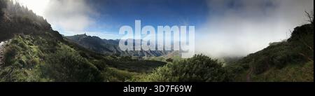 Ein Panorama mit üppigen grünen Hügeln und weiten Tälern unter einem dramatischen Himmel, der teilweise von Wolken bedeckt ist, schafft ein Gefühl von Ruhe und offener Landschaft Stockfoto