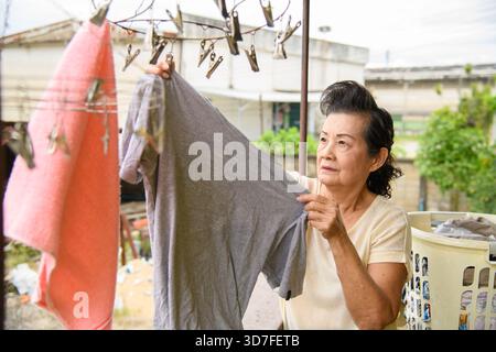 Grandma hängt Kleidung zum Trocknen auf dem Balkon. Stockfoto