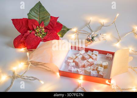 Türkische Delikatesse im Geschmack von Rose, Zitrone und Orange auf weißem Hintergrund mit Weihnachtslichtern, Weihnachtskaninchen und Weihnachtsstern Stockfoto