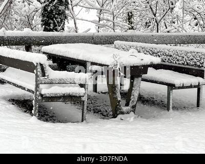 Tisch und Bänke im Winter in einem Stadtpark mit Schnee bedeckt. Winterszene. Ruhebereich nach Schneesturm nicht genutzt. Stockfoto