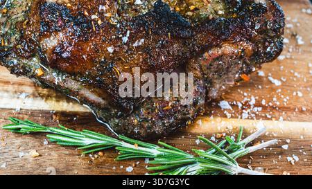 Saftiger ganzer, knochenloser Lammbraten mit Kräutern und Rosmarin auf Holzbrett. Perfekt gewürzt, saftig und bereit zum Schnitzen für besondere Anlässe Stockfoto