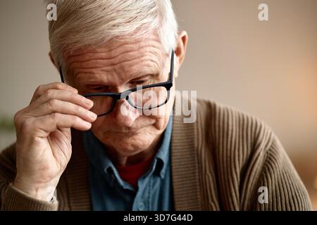 Seniorenmann Trägt Nachdenklich Eine Brille Drinnen Stockfoto