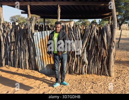 Dorf einzelne afrikanische junge Männer, die vor einer Holzhütte stehen, im Hof Stockfoto
