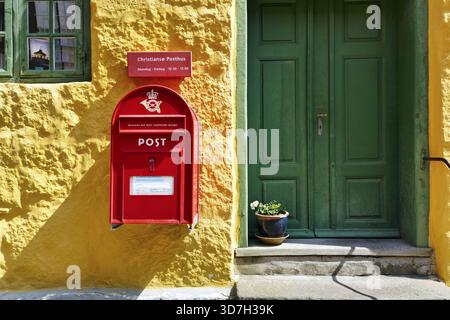 Post, Fassadendetail, roter Briefkasten mit Posthorn und Krone, grüne Holztür, gelbe Wand, Christianso, Christiansoe, Ertholmene, Pea Islands Stockfoto