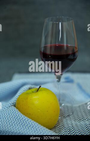 Stillleben mit gelbem Apfel und Rotwein Stockfoto