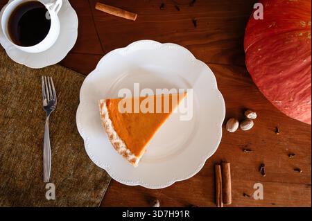 Ein Stück Kürbiskuchen mit Kaffee auf einem Holztisch Stockfoto