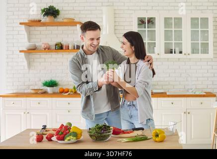 Glückliches Paar Kocht Zusammen Mit Gemüse In Der Küche Zu Hause Stockfoto