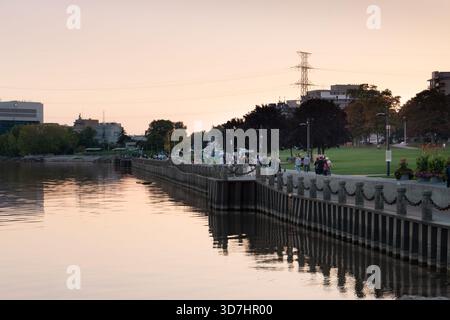 Malerischer Blick auf das Wasser in der Abenddämmerung, mit Leuten, die entlang der Promenade spazieren. Burlington, EIN Stockfoto