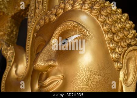 Nahaufnahme der goldenen Buddha-Statue mit heiterem und friedlichem Ausdruck. Diese antike Skulptur repräsentiert Religion, Spiritualität, Glauben und Medizin Stockfoto