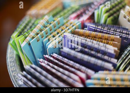 Nahaufnahme der farbenfrohen Sammlung kleiner spiralförmiger Notizblöcke mit verschiedenen Mustern. Dieses Sortiment an Schreibwaren in Tablett inspiriert Kreativität und Kreativität Stockfoto