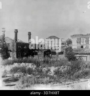 Slawjansk, Region Donezk, ukrainische SSR, Sowjetunion. 1943. Die Ruinen der Artem Armature-Isolator Factory (AIZ) nach der Befreiung der Stadt von der Nazi-Besatzung während des Zweiten Weltkriegs. Das Foto zeigt zerstörte Industriegebäude mit drei Kaminen und eingestürzten Dächern. Leere Fensteröffnungen schlagen in den Ziegelwänden. Unkraut wächst im Vordergrund zwischen den Trümmern. Dieses seltene Archivbild dokumentiert die katastrophale Zerstörung der Donbass-Industrie vor dem Wiederaufbau nach dem Krieg. Stockfoto