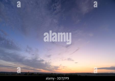 Ein atemberaubender Blick auf einen ruhigen Sonnenuntergang mit atemberaubenden Wolken, die anmutig über einer friedlichen Landschaft schweben Stockfoto