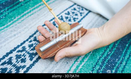 Eine Person, die einen Glockenhammer hält, der auf ein Klangheilinstrument trifft Stockfoto