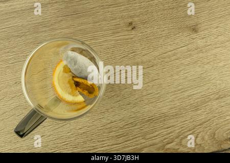 Sternanis, Zimtstangen, Tee und ein in Scheiben geschnittenes ​​orange in einem leeren Glas auf einem Holztisch, Zutaten für einen warmen Wintertee Stockfoto