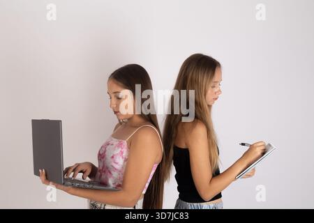 Mädchen benutzen elektronische Geräte hintereinander. Stockfoto