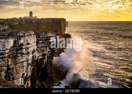Peniche Portugal 9. November 2025. Große Atlantikwellen krachen bei Sonnenuntergang gegen hohe Klippen unter einem Leuchtturm. Stockfoto
