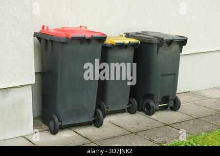 Müllsortierung in Europa. Mülltonnen mit bunten Deckeln für verschiedene Müllarten Stockfoto
