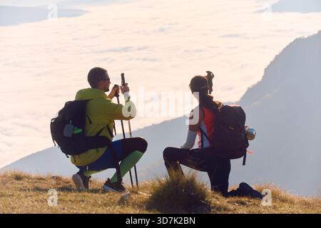 Wanderer nehmen sich einen Moment Zeit, um die Aussicht während ihrer Wanderung über die Wolken in einer Berglandschaft bei Sonnenaufgang zu genießen Stockfoto