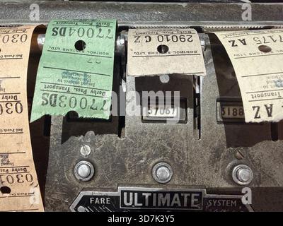 Nahaufnahme eines klassischen mechanischen Fahrkartenautomaten mit alten Papierbustickets in verschiedenen Farben und Seriennummern Stockfoto