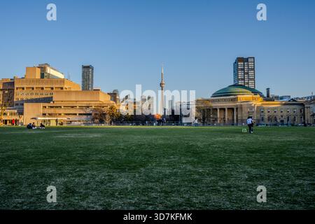 Die Menschen versammeln sich auf dem Rasen des Front Campus an der University of Toronto, wobei der CN Tower und die Convocation Hall in der Ferne während einer klaren Ebene sichtbar sind Stockfoto