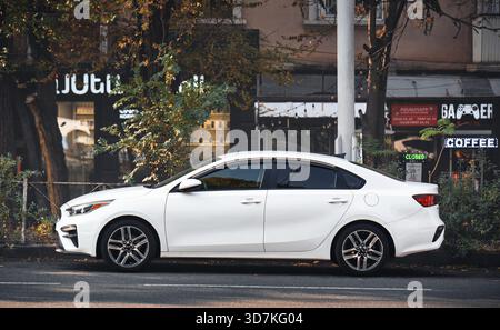Jerewan Armenien 11.20.2025. Ein weißes Auto parkt am Straßenrand vor einem Café. Das Auto steht vor einem Gebäude mit einem s Stockfoto
