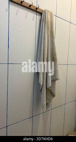 Beigefarbenes Handtuch auf einem Holzhakenständer im Badezimmer Stockfoto