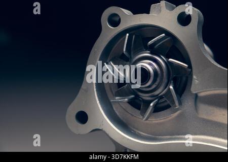 Nahaufnahme einer neuen Kühlwasserpumpe des Verbrennungsmotors auf grauem Hintergrund. Kontrastlicht Stockfoto
