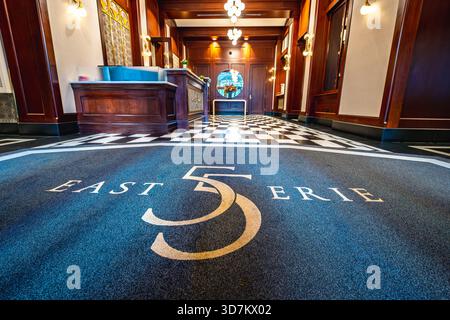 Luxuriöse Lobby mit kariertem Marmorboden, Holztäfelung und Eingangsmatte „East 55 Erie“. Stockfoto